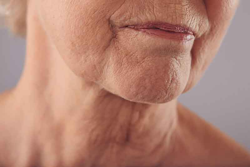 Woman with closed eyes holds her hand on her neck